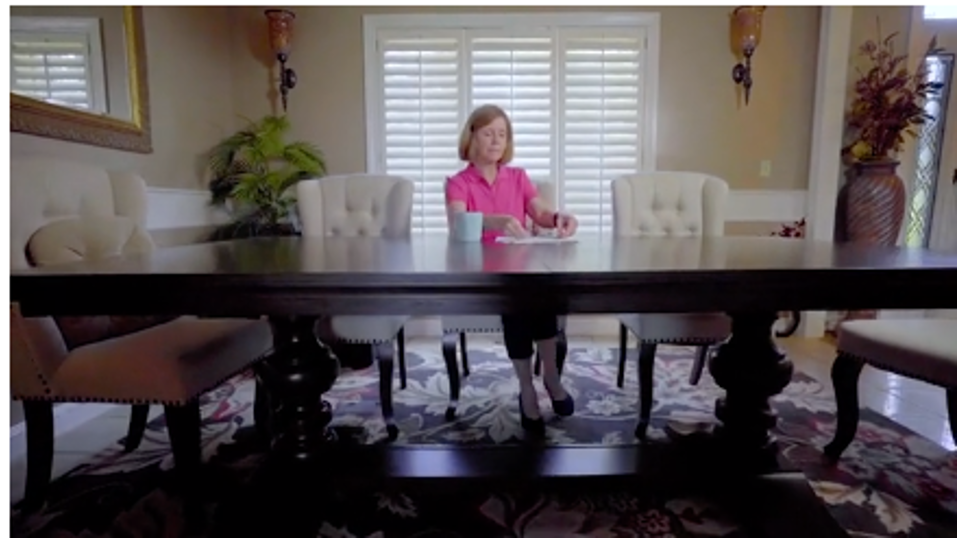 lady sitting at a large table with a cup of coffe and papers infront of her
